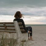Femme seule sur un banc face à la mer